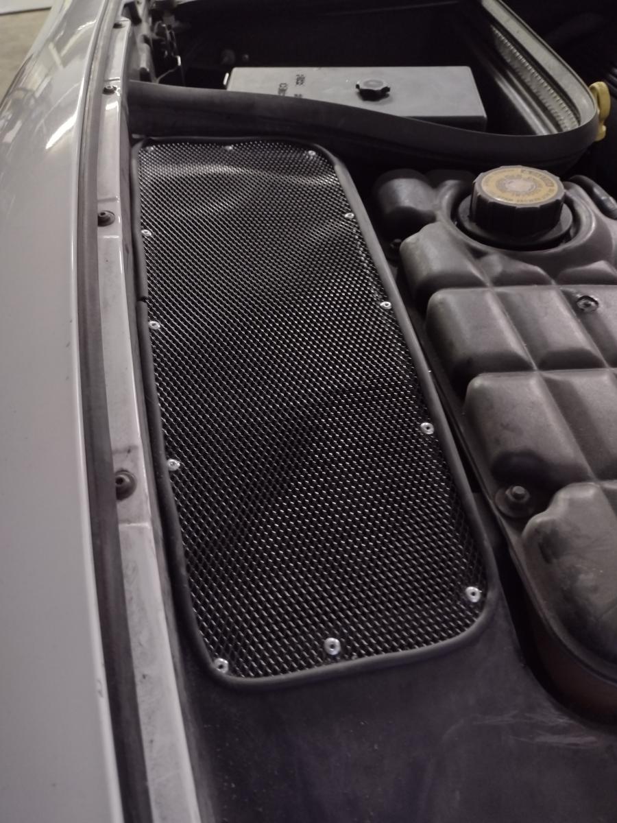 The top of passenger side wheel well of a 1999 C5 Corvette, which has been modified with a vent to allow air to escape upwards through the hood vents.