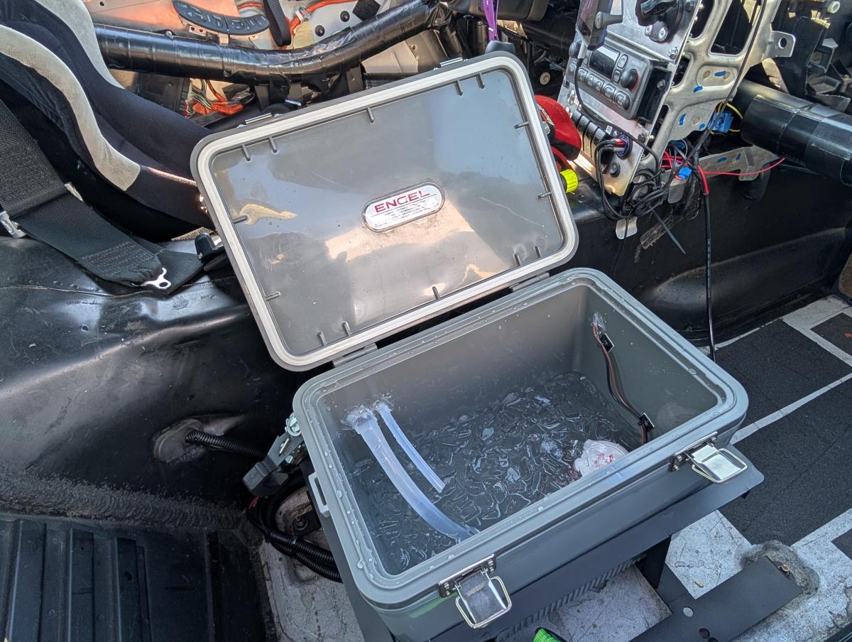 Our DIY c5 corvette cool shirt cooler open in the passenger seat of the corvette. It's full of ice and water and good to go!