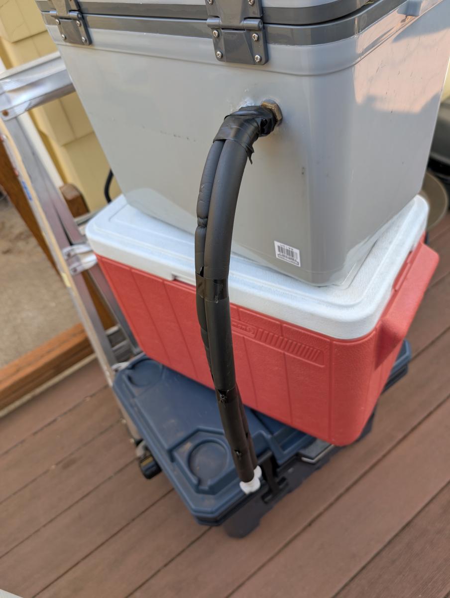 A zoomed out photo of the hose connections and hoses coming out of our DIY cool suit cooler