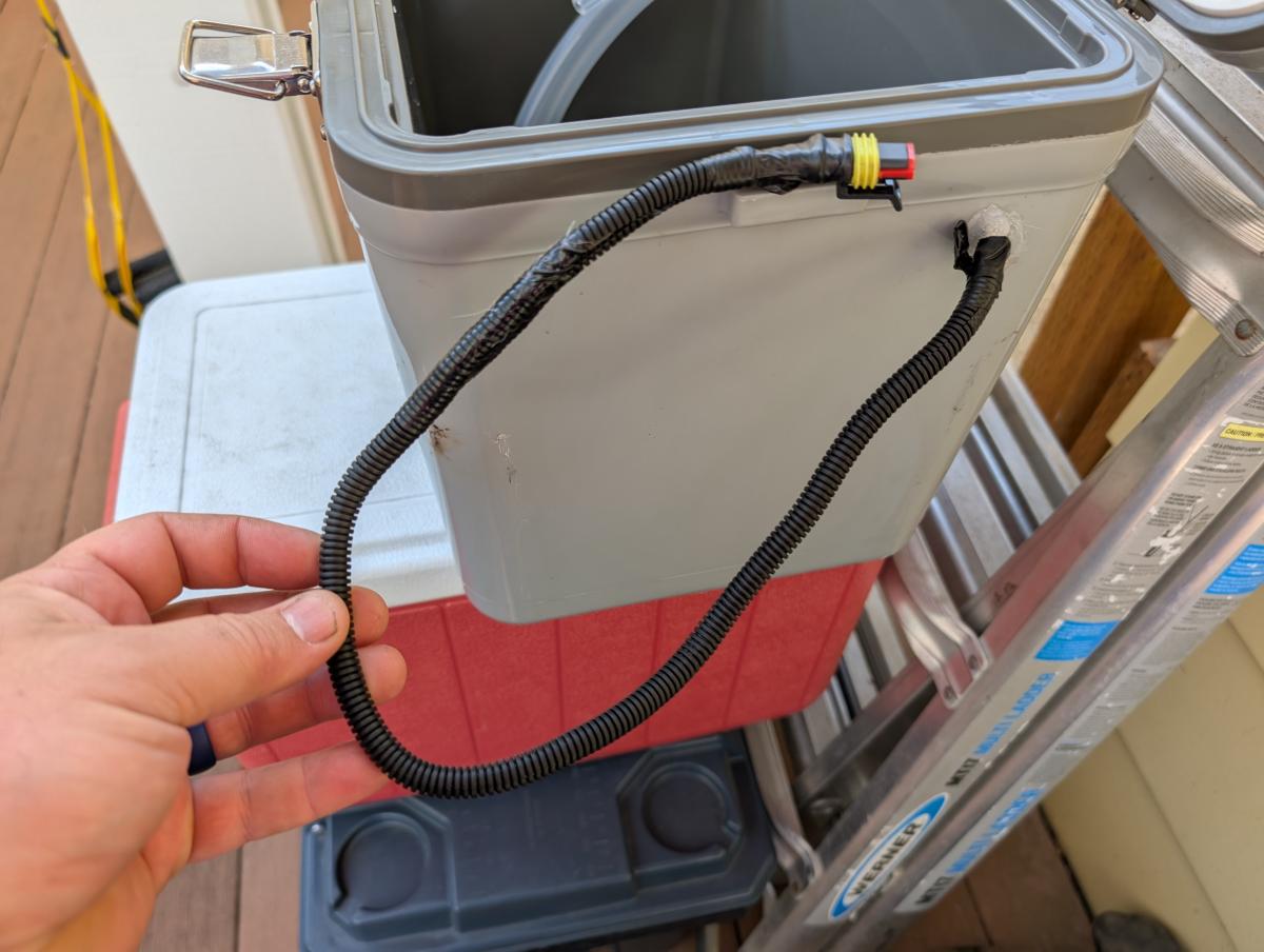 The wiring exiting the diy cool shirt cooler, wrapped in wire loom and with a waterproof electrical connector on the end.