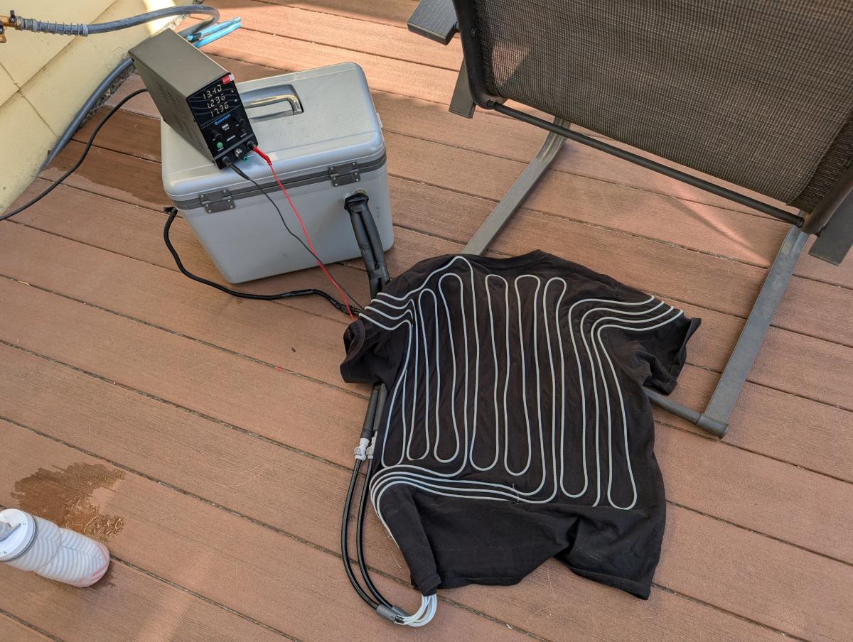 A DIY Cool Shirt Setup with the shirt attached and a power supply providing power to the Cooler pump.
