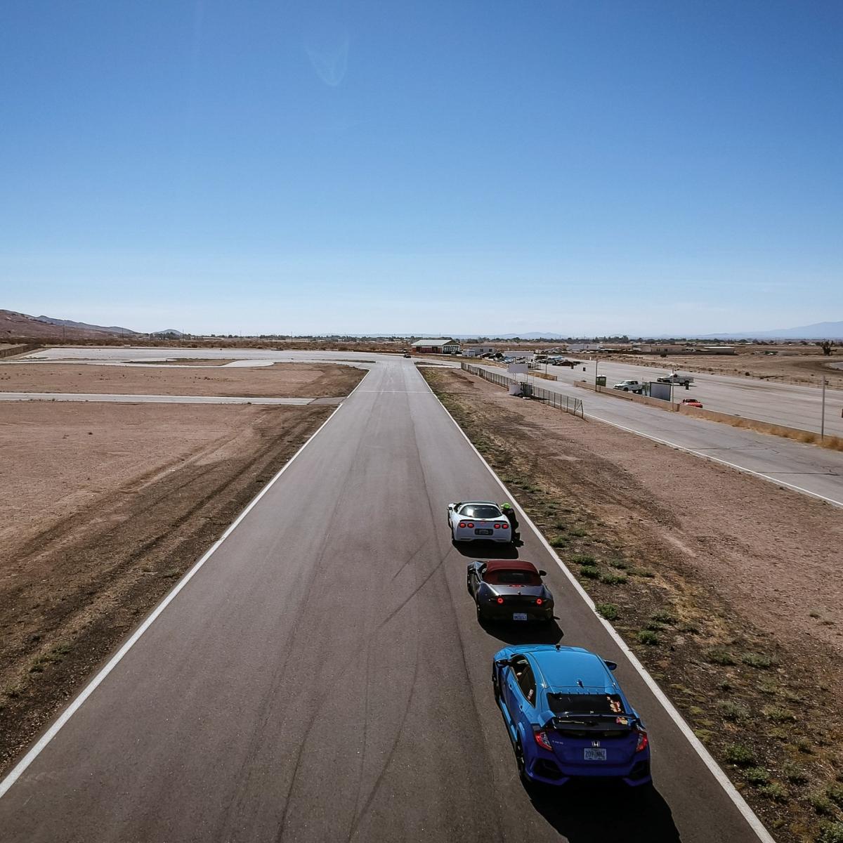 Cars in line on the front straight waiting to try a drill on the Skid Pad at Streets of Willow Springs. Jesse's White 99 Corvette is front of the line.