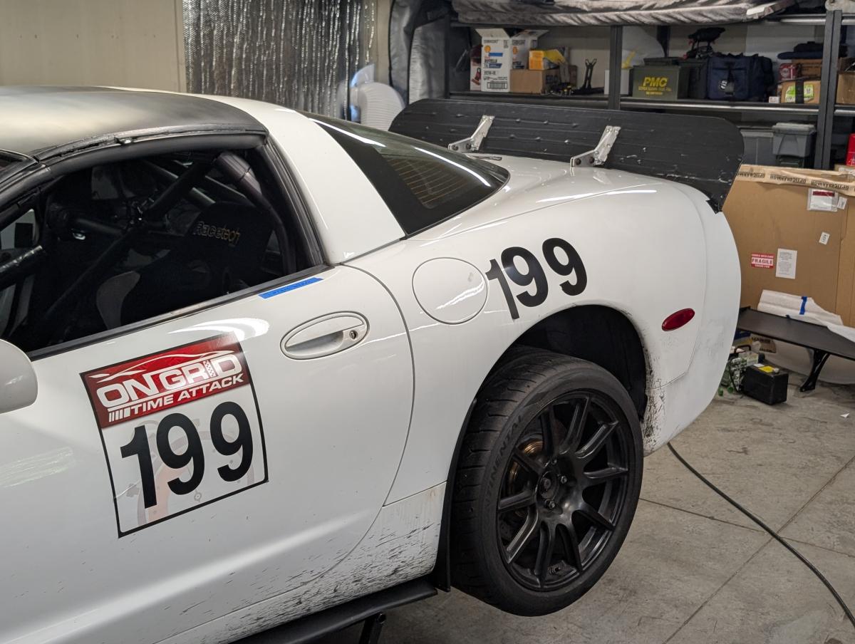 White C5 Corvette in Shred Jesse's shop, with spoiler covered in black gorilla tape.