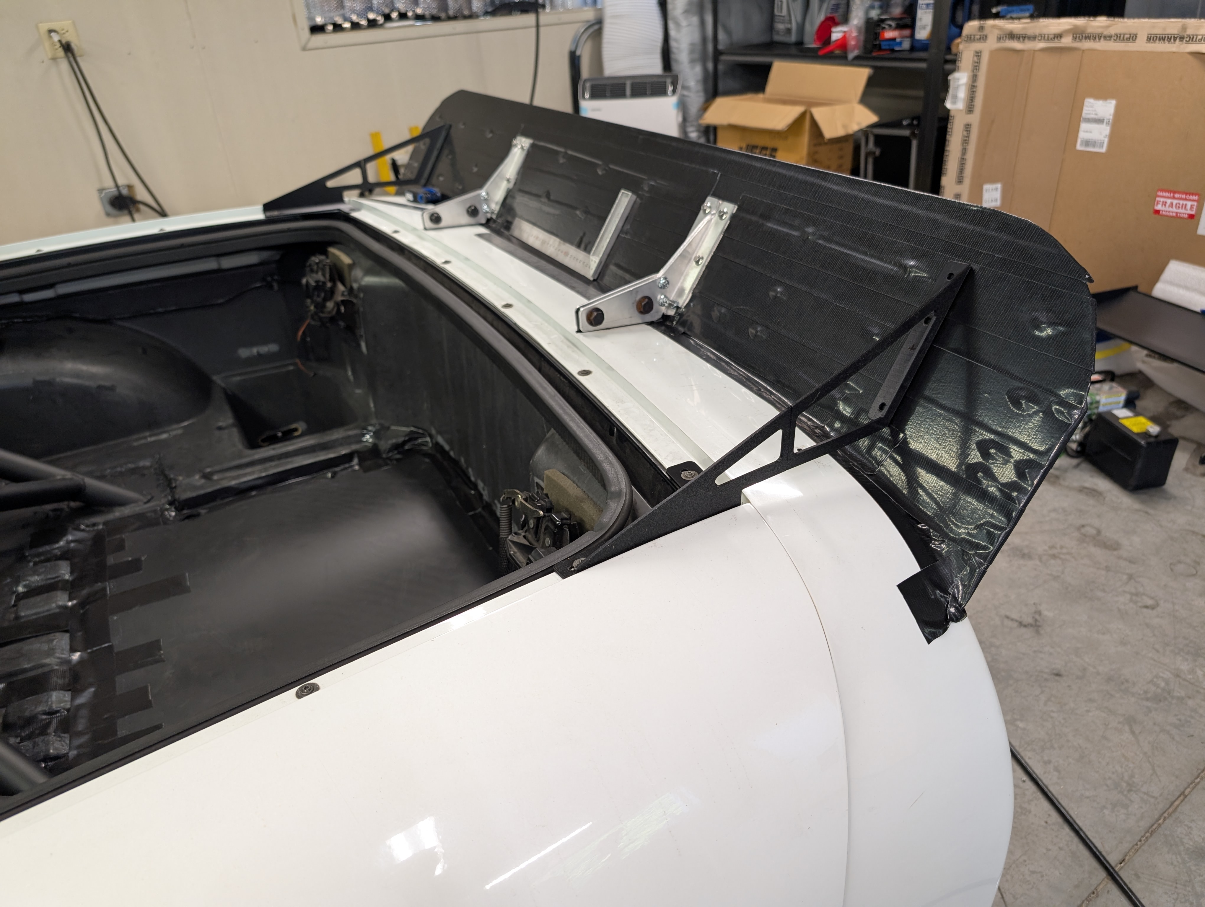The rear spoiler on a c5 corvette, with the hatch open, demonstrating the final version of the spoiler brackets both to the chassis mounts and to the hatch screws.