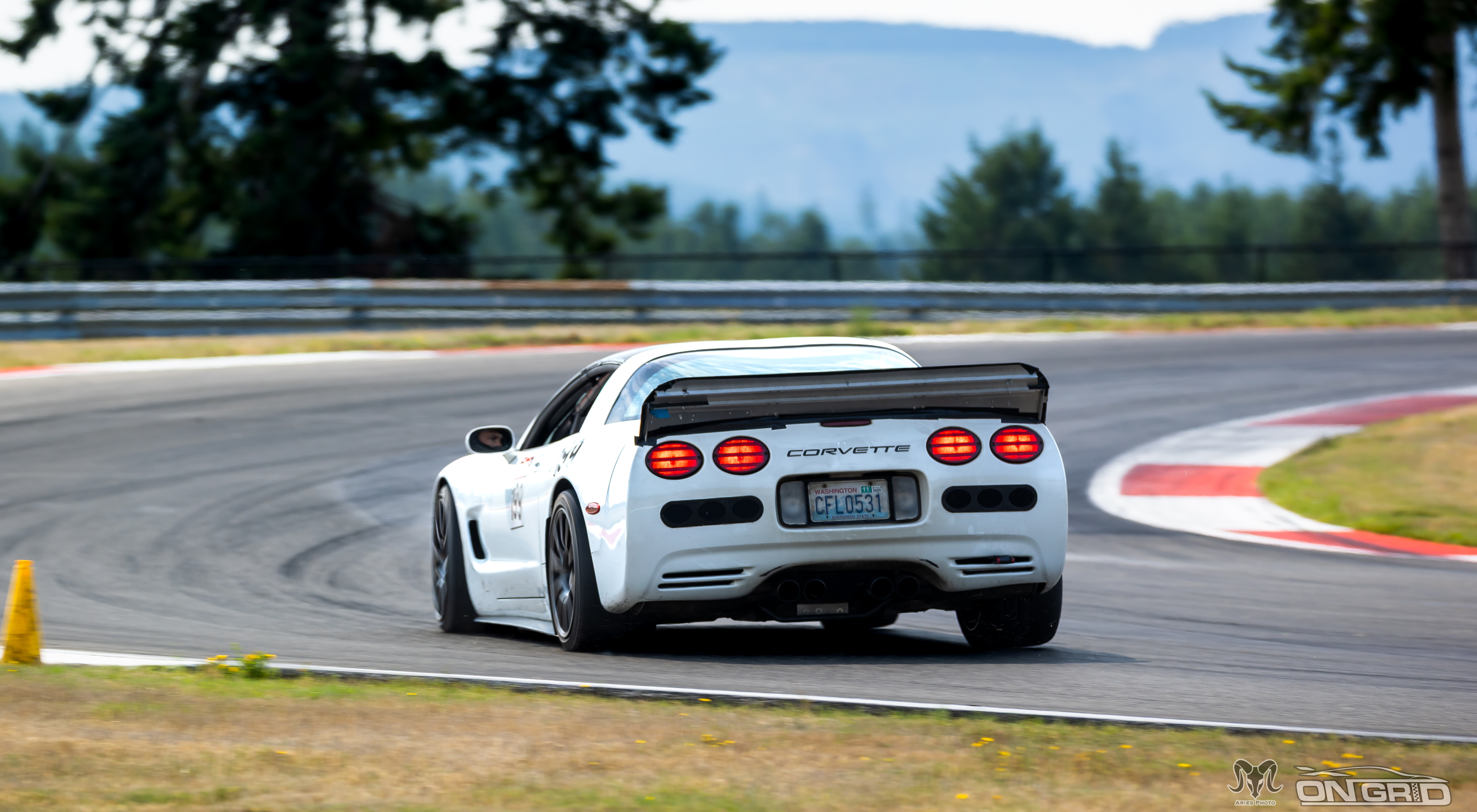 Rear shot of a white C5 Corvette at the ridge, with suspension loading as it begins turn in.