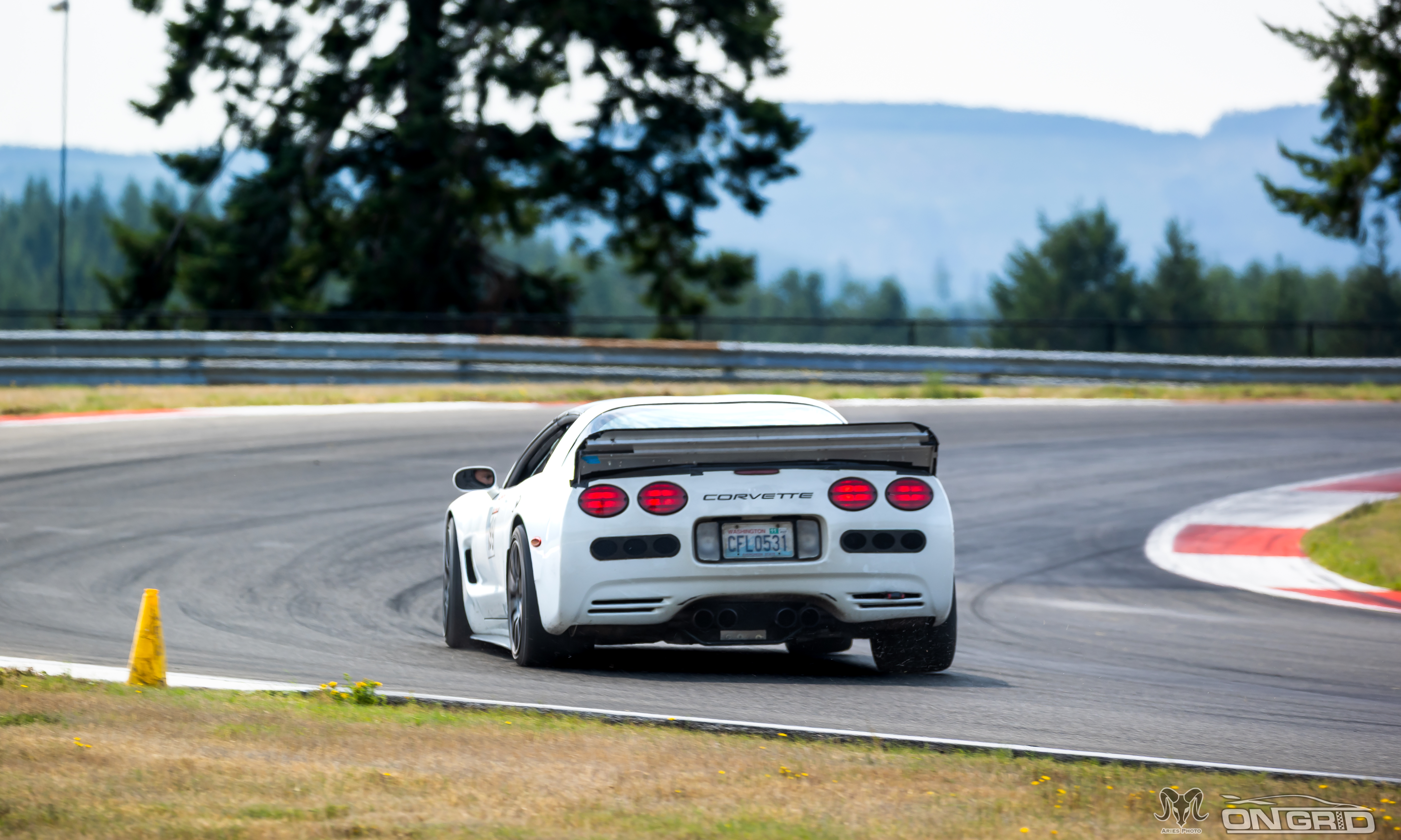 Rear shot of a white C5 Corvette at the ridge, weight unloading as suspoension settls and turn begins.