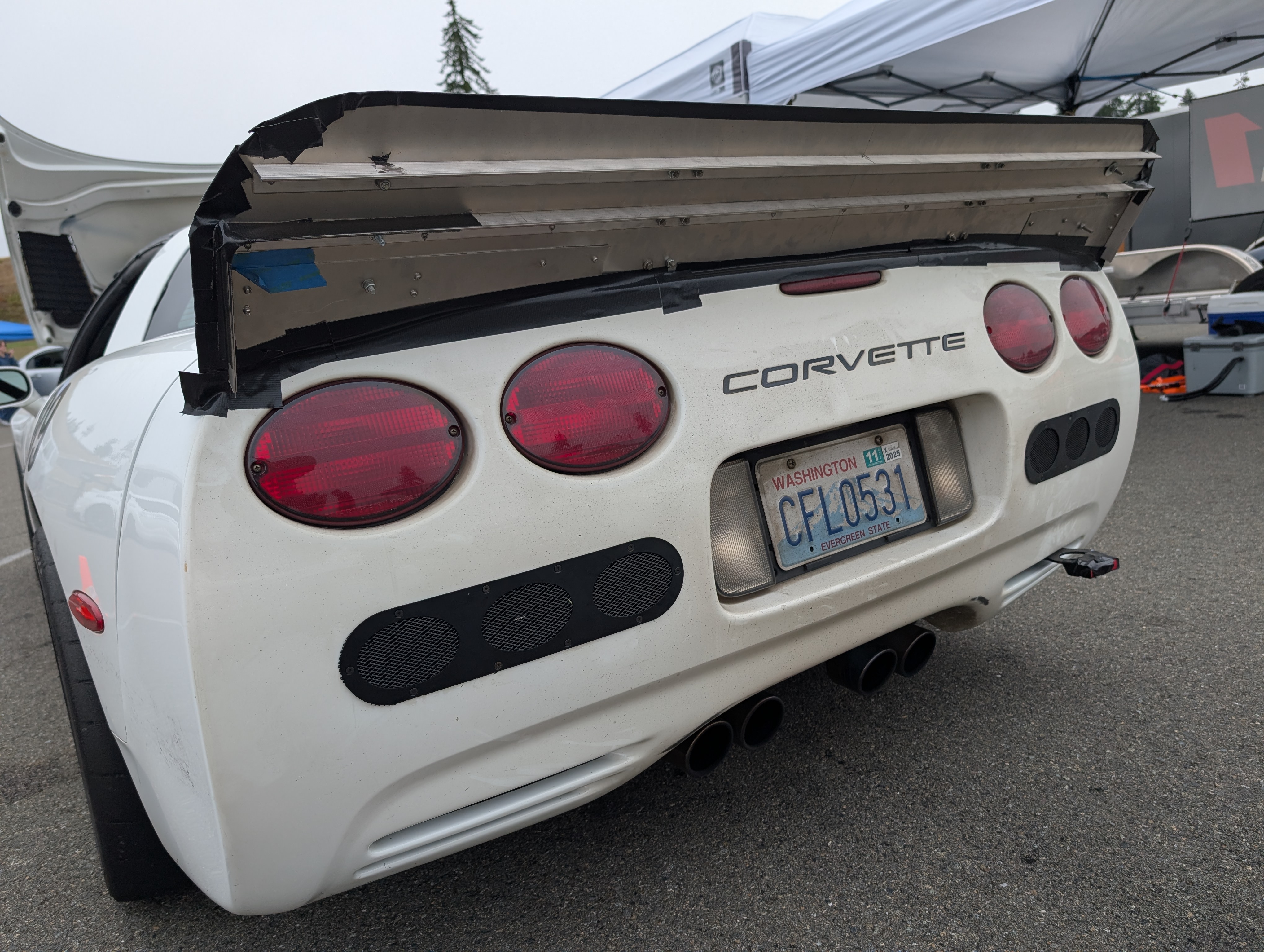 A rear view of the DIY spoiler, which is bare metal and showcases how two pieces of angle aluminum were used to run the length of the spoiler to increase rigidity.