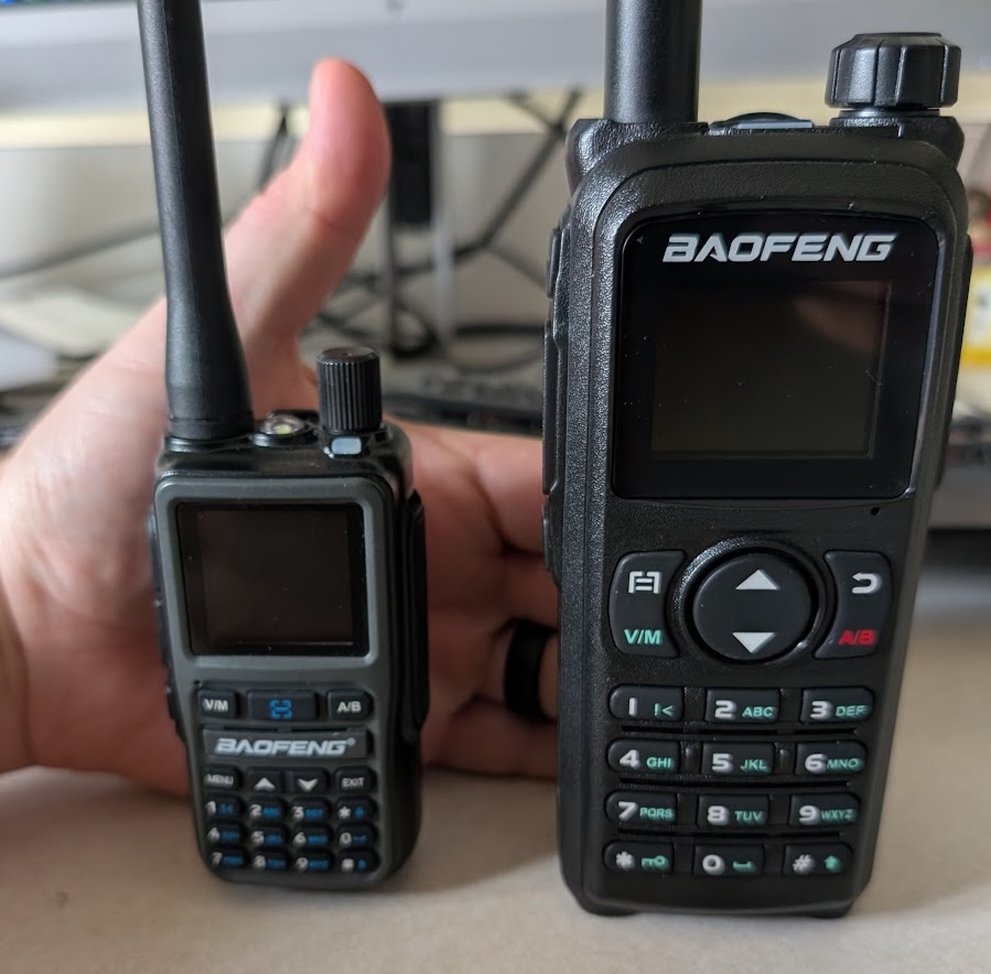 A picture of the UV-5R mini and UV-28+ in front of a hand ,demonstrating hat the UV-28+ is over twice the size of the UV-5R mini