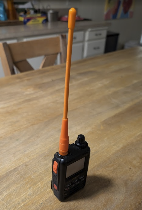 A Yaesu FT5DR handheld with a "medium" sized bright orange HYS 7.8" Antenna