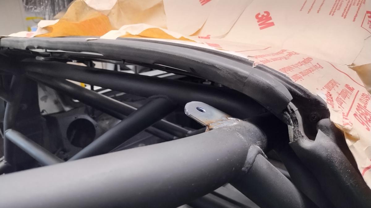 A rear mounting tab for securing the targa top of a C5 Corvette to the Trackspec C5 Corvette roll cage.
