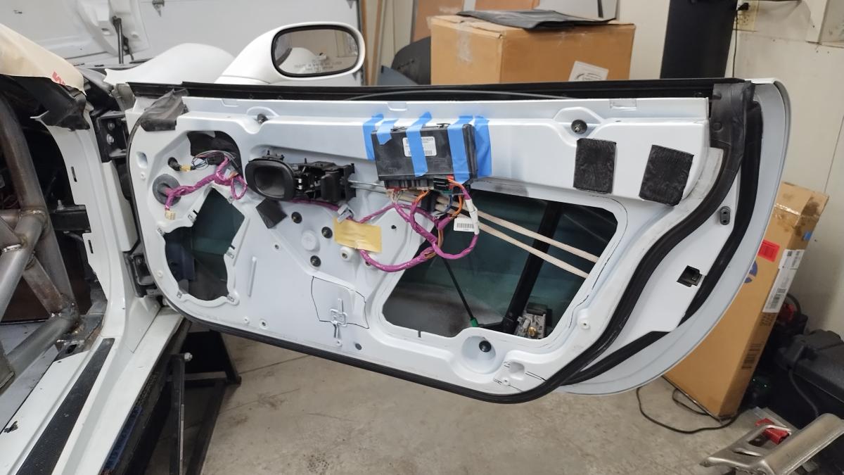 A gutted and open C5 Corvette passenger door, with two areas highlighted for where they impact the Trackspec C5 corvette rollcage