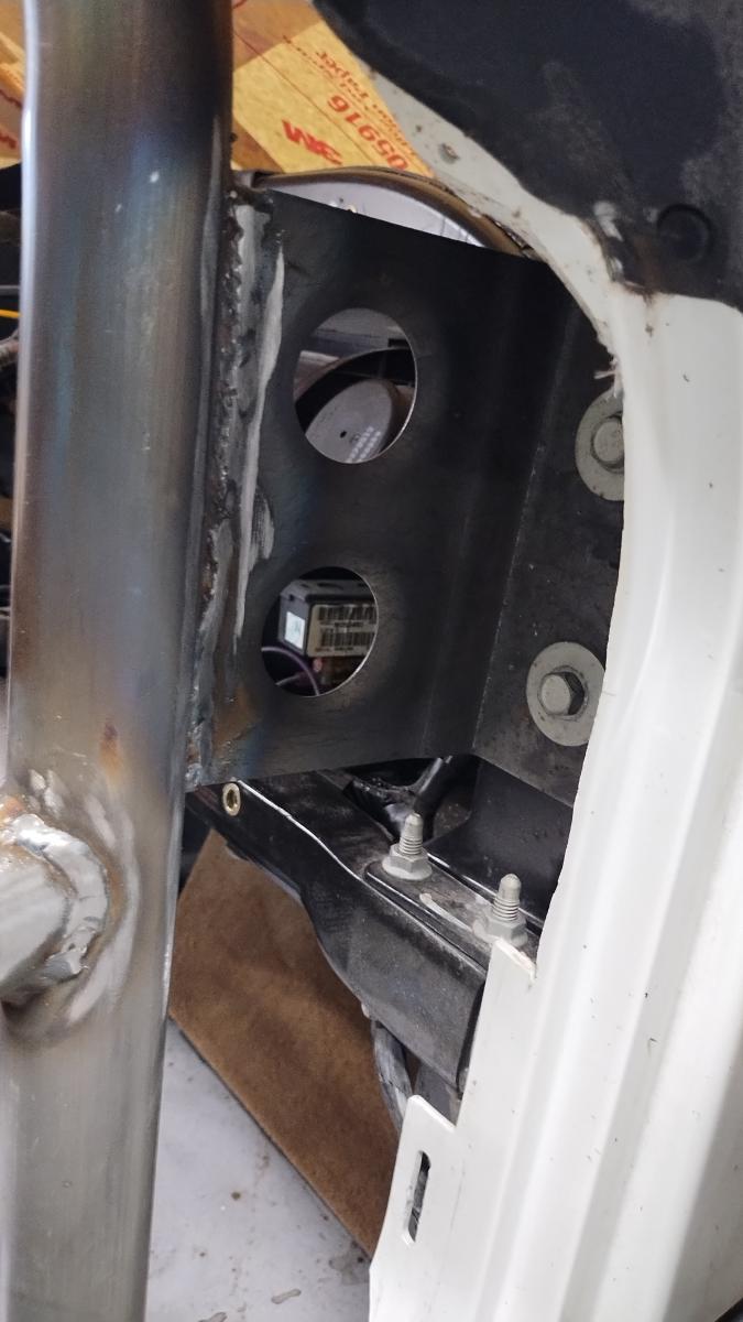 A custom L shaped bracket on the passenger side  attaching the front windshield support of the C5 Corvette Trackspec Rollcage to the chassis of the Corvette