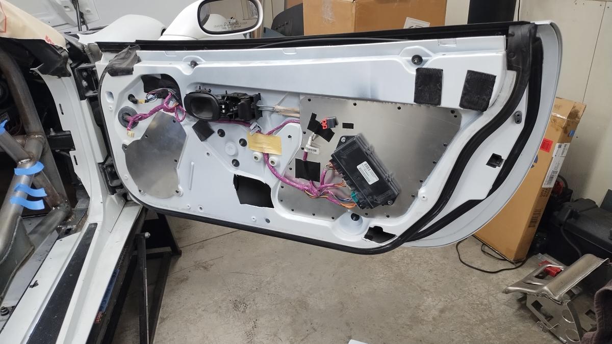 The passenger side door, notched and with the large factory openings closed up with aluminum sheet metal.