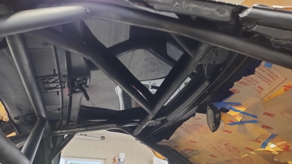A view from underneath of a C5 Corvette Targa top secured to the Trackspec roll cage, demonstrating the custom tabs welded in by Shred Jesse